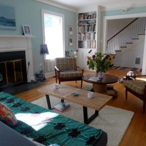 Airbnb Living Room with Couch, Wooden Table, Chairs, Flowers, Window and Stairs