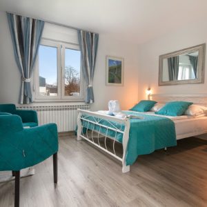 Airbnb Bedroom view, with Bed, Sofa, blue Pillows, Frame, Window with grey Curtains